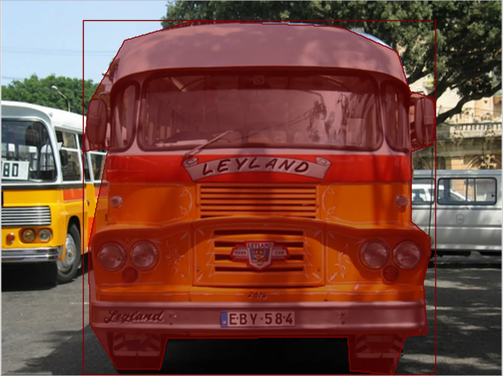 Offscreen Labelme canvas showing the same orange bus as a filled translucent red mask shape, with the mask's bounding-box outline drawn around it.